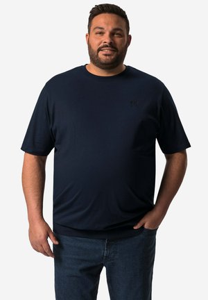 Marineblauw T-shirt met korte mouwen, een relaxte pasvorm, ronde hals, en een klein zwart logo op de borst, gecombineerd met blauwe spijkerbroek.