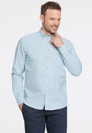 Camisa de botones a rayas azul claro y blanca con un pequeño bolsillo en el pecho y dobladillo redondeado. Manga larga con puños abotonados.