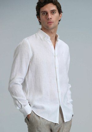 White linen long-sleeve shirt with a button-down collar, featuring a relaxed fit and subtle texture. Paired with light beige striped trousers.