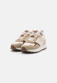 Beiga och bruna sportskor i en blandning av mocka och syntetmaterial. Utrustad med snören, guldhardware och en prickig vit sula.