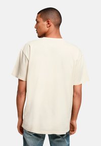 Beige Baumwoll-T-Shirt mit lockerer Passform, kurzen Ärmeln und crew-neck, mit einer glatten Textur und einfachem Design.