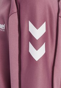 Roze sportstof met gestructureerd oppervlak, voorzien van wit chevronpatroon en logo. Contrasterende donkere stiksels langs de naden.