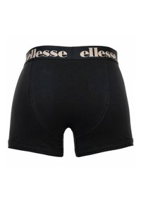 Boxers noirs pour hommes avec un logo beige "ellesse" sur la ceinture élastique, vus de dos.