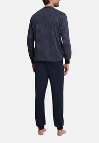 Navy pajama set featuring a patterned long-sleeve top and solid bottom. Soft fabric with elastic cuffs and waistband for comfort.