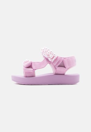 Light purple children's sandal with adjustable straps decorated with white pearls on a white background.