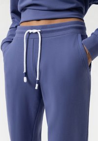 Paarse sweatpants van zachte stof, met een trekkoord in de taille met witte accenten, zijzakken en geribde boorden.