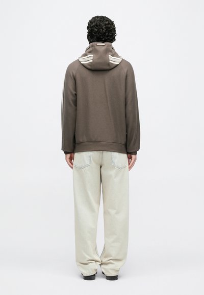 Καφέ φούτερ με κουκούλα, με αντιθετικές ρίγες στην κουκούλα και ανοιχτόχρωμα, φαρδιά τζιν. Απλός, καθαρός σχεδιασμός.