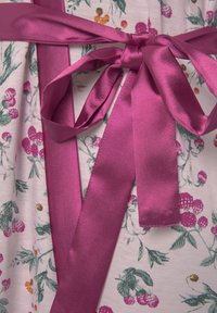 Tessuto con motivo floreale in morbido bianco con accenti rosa e verdi, caratterizzato da un ampio nastro di raso fucsia lucido legato in vita.