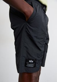 Shorts noirs en tissu léger, dotés d'une poche plaquée avec logo et d'une taille élastique pour le confort.