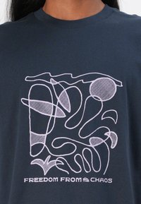 Navy cotton t-shirt featuring a white line drawing with abstract shapes and the text "FREEDOM FROM THE CHAOS" at the bottom.