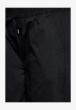 Pantaloni corti neri leggeri con vita elasticizzata, cordoncino regolabile e texture liscia. Presentano dettagli delle cuciture sui lati.