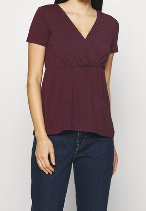 Bordeaux kortærmet top med V-hals og samlet talje. Lavet af blødt stof, har den en afslappet pasform og glat tekstur.