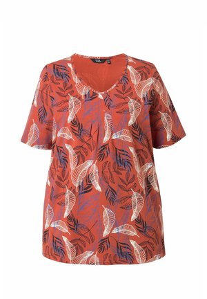 Blouse rouge à manches courtes avec col en V, avec des motifs de feuilles blanches, noires et bleues sur l'ensemble du tissu.