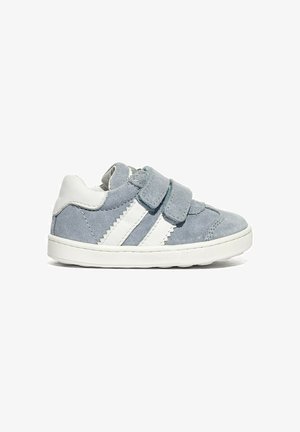 Sneaker grigia in pelle scamosciata per bambini con strisce bianche, due cinturini in velcro e suola bianca, vista dal lato esterno su sfondo bianco.