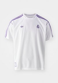Vit tröja med vertikala ränder, lila accenter och rundad halsringning. Har Adidas-logotypen på vänster bröst och Real Madrid-klubbmärke på höger.