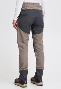 Broek met een beige bovenstuk en een donkergrijs onderstuk, met een getailleerd ontwerp en verstelbare manchetten, gemaakt van een duurzaam materiaal.