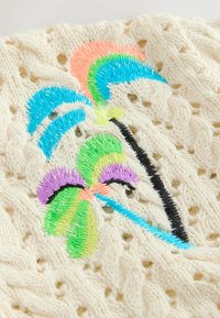 Tissu tricoté crème avec des motifs de palmiers brodés colorés en fils bleu, vert, violet et pêche.