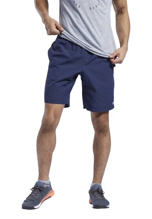 Pantalones cortos deportivos azul marino con cinturilla elástica y bolsillos laterales, combinados con una camiseta gris de manga corta y zapatillas deportivas grises.