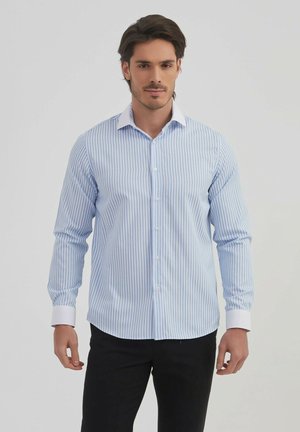 Chemise à manches longues rayée bleu et blanche avec un col et des poignets blancs, dotée d'une fermeture à boutons et d'une silhouette ajustée.
