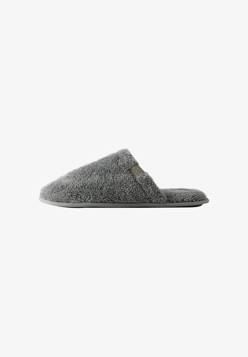 Gray fleece slipper with a textured upper, open toe design, and a flexible rubber sole. Features a small, rectangular accent detail.