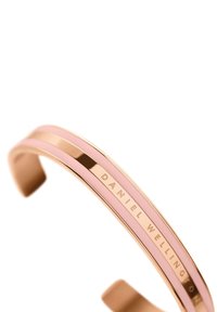 Rožu zelta aproce ar gludu virsmu, kas papildināta ar rozā ieliktni un gravētu "DANIEL WELLINGTON" detaļu iekšpusē.