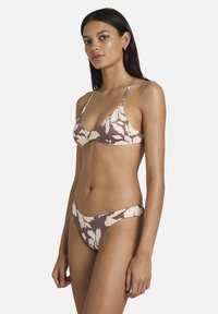 Bikini floral marron et crème avec fines bretelles et haut triangle ; présente une texture lisse et un design à couverture minimale.
