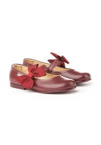 Un par de zapatos Mary Jane de piel burdeos con grandes lazos de tela en la correa, forro interior beige y tacones planos sobre fondo blanco.
