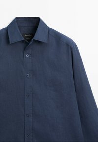 Navy blue long-sleeve linen shirt with a pointed collar and visible buttons down the front.