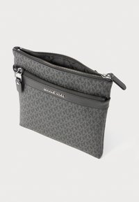 Pochette zippée grise avec un design à motifs. Présente un accent en cuir noir et une plaque logo en argent. Texture lisse et fermeture sécurisée.