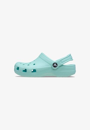 Crocs de color teal claro con un diseño perforado y correa, fabricados en material ligero. Presentan un botón de logo en el lateral y una suela texturizada.