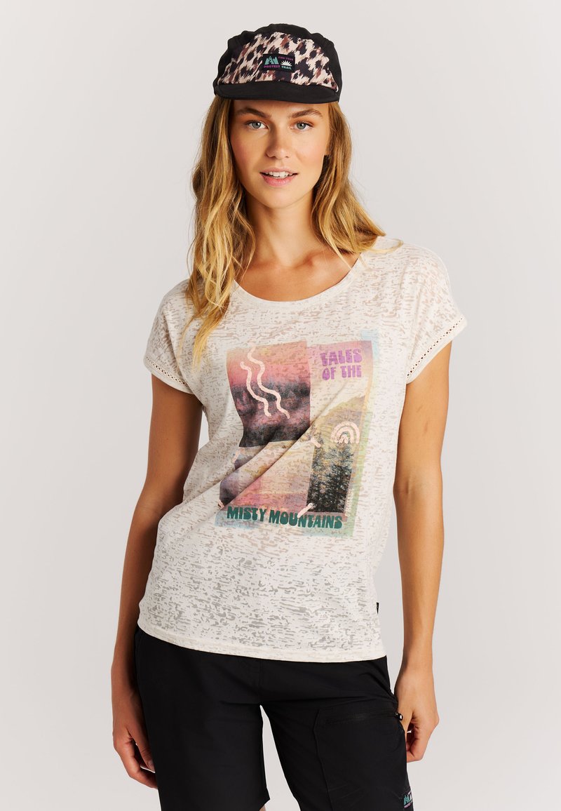 T-shirt blanc texturé avec un design graphique comprenant des formes colorées et le texte "TALES OF THE MISTY MOUNTAINS". Casquette noire avec imprimé léopard.