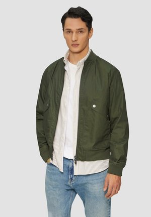 Olivgrüne Bomberjacke mit Fronttaschen, gerippten Bündchen und Reißverschluss. Tragen Sie sie über einem weißen Hemd und blauen Jeans, mit einer lässigen Passform.