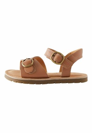 Brun lädersandal med justerbara remmar, runda metalliläggningar, vadderad sula och en texturerad gummisula.