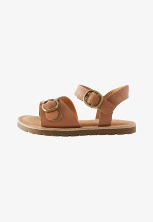 Braune Ledersandalen mit verstellbaren Riemen, kreisförmigen Hardware-Akzenten, gepolstertem Fußbett und einer strukturierten Gummisohle.