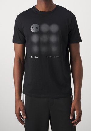 T-shirt en coton noir avec un graphique rond portant "A|X" et des points texturés, accompagné des mots « milano », « new york » et « armani exchange ».