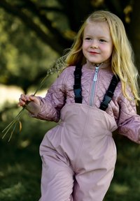 Lengvai rausvos spalvos siūtas švarkelis su užtrauktuku ir juodomis petnešomis; derinamas su tokios pačios spalvos vandeniui atspariais apsiaustais. Vaikas laiko augalą.