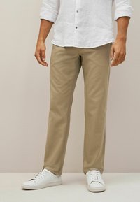 Beiga chinos med slim fit, tillverkade av mjukt material, med en ren design. Kombinerat med vita sneakers för en avslappnad look.