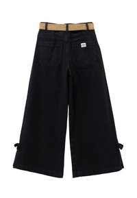 Pantaloni larghi neri con una cintura glitter oro, dotati di due tasche posteriori e dettagli a fiocco all'orlo. Materiale in cotone con una texture liscia.