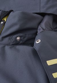 Granatowa kurtka z tkaniny o gładkiej teksturze, z żółtymi akcentami, z zatrzaskami i kieszenią wewnętrzną, zaprojektowana z myślą o funkcjonalności i ciepłu.