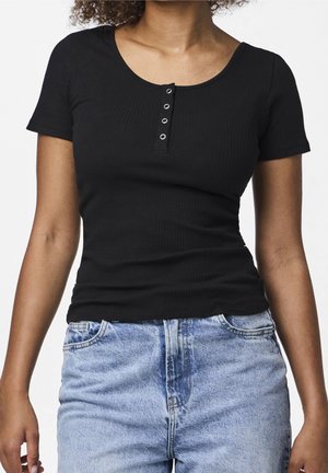 Femme portant un haut noir moulant à manches courtes côtelé avec quatre boutons, associé à un jean taille haute bleu clair.