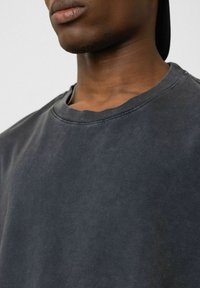 Donkergrijze sweatshirt met een ronde hals, gemaakt van zachte stof. Het heeft een vervaagde textuur en minimale stikseldetails.