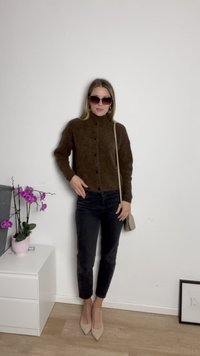 Cardigan marrón de punto con botones negros, combinado con jeans negros y tacones de punta beige. Los accesorios incluyen gafas de sol y un bolso pequeño.
