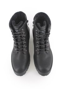 Botas de tobillo negras de cuero, con un interior acolchado, parte delantera con cordones y ojales metálicos. Suela de goma gruesa y cierre con cremallera.