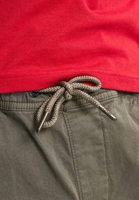 Rode katoenen t-shirt, gecombineerd met kaki broek met een gevlochten trekkoord en een metalen label, die een soepele textuur en een casual ontwerp uitstralen.