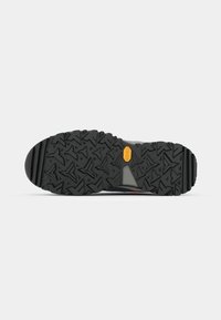Sort gummiydersål med dybt mønster, der har hævede geometriske designs og et gult Vibram-logo nær hælen.