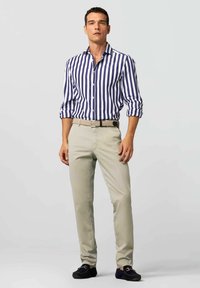 Striped blue and white button-up shirt with rolled sleeves, paired with light beige chinos and dark slip-on shoes. Simple belt included.