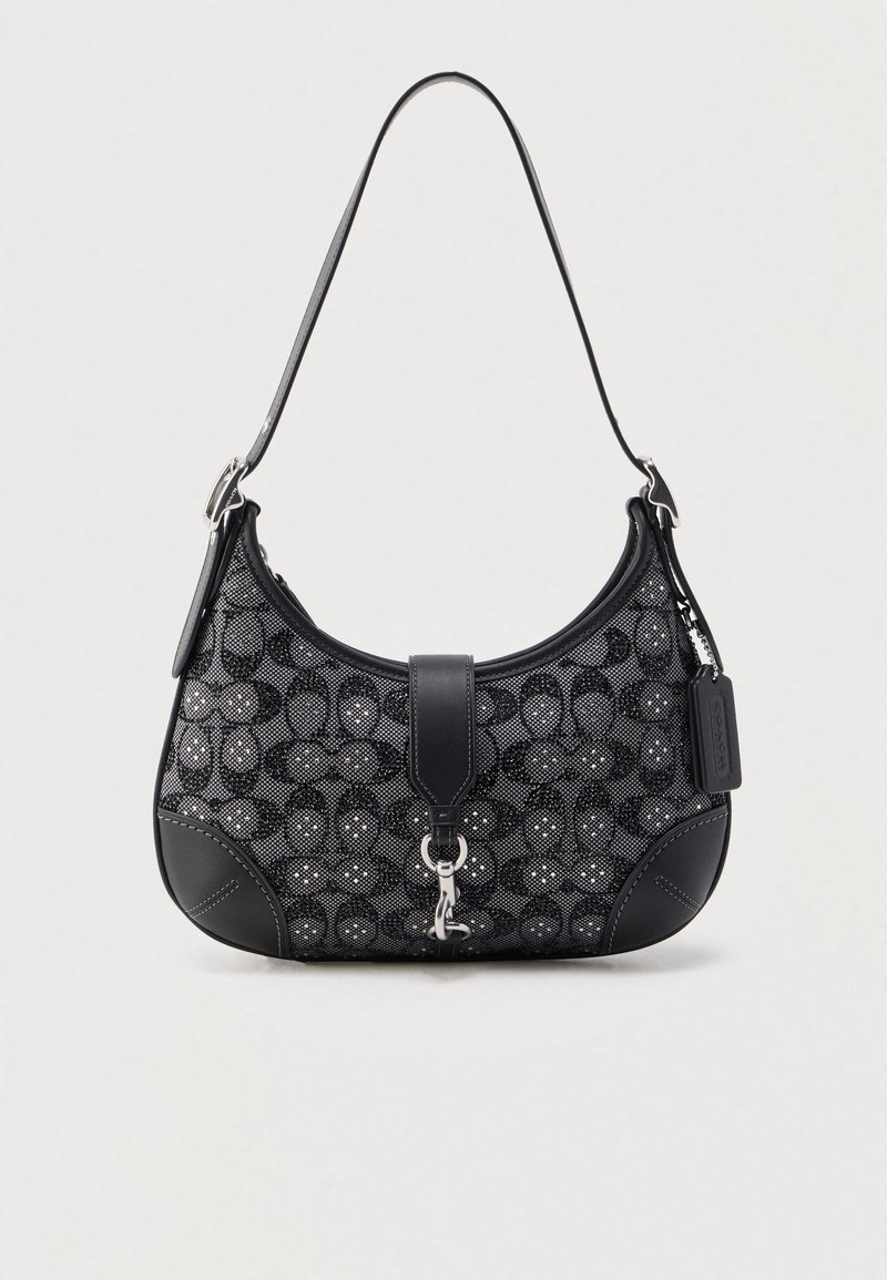Μαύρη τσάντα χειρός με υφασμάτινο μοτίβο κυκλικών σχεδίων, δερμάτινες λεπτομέρειες, επίπεδο ιμάντα ώμου και μεταλλικό κούμπωμα.