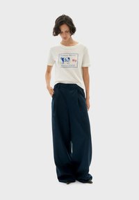 Witte korte mouwen t-shirt met een blauwe grafische print en navy hoge taille wijde broek, met zijzakken en een getailleerde pasvorm.