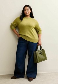 Oliwkowy sweter z dzianiny, luźny krój, szerokie ściągacze; ciemnoniebieskie dżinsy o szerokich nogawkach; usztywniona ciemnozielona torebka o fakturze krokodyla.