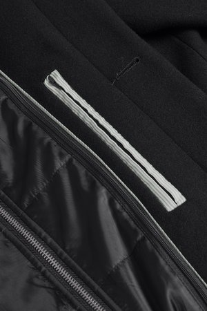 Black jacket interior showing nylon lining, zipper details, and a contrasting white stripe. Soft texture with quilted sections.
